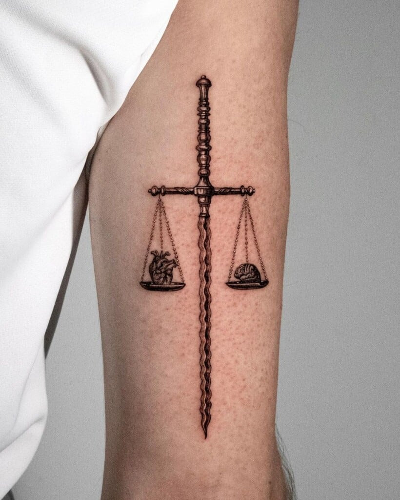 Heart, brain, scales, and sword tattoo representing balance between emotion and logic, compassionate decision-making, and justice.