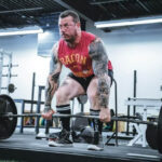 deadlifting barbell with arm sleeve tattoo