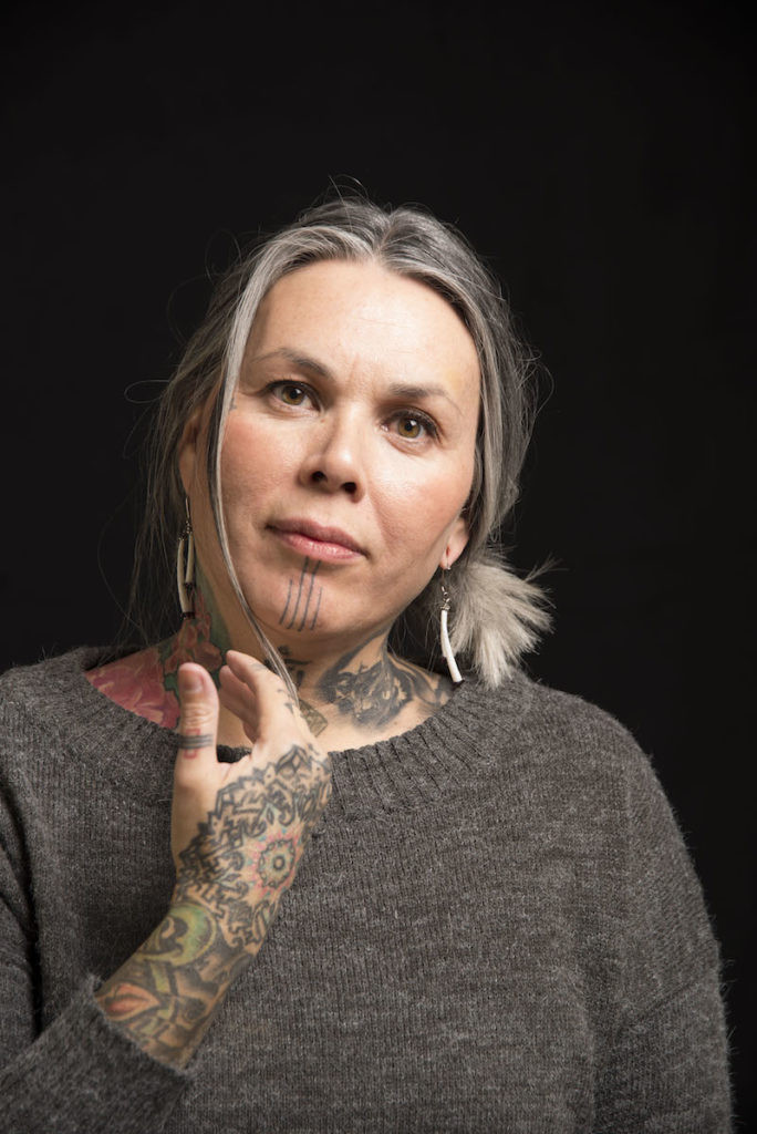 Maya Sialuk Jacobsen, a Greenlandic Inuit tattoo artist, poses holding traditional tattooing tools, embodying the revival of ancient art forms.