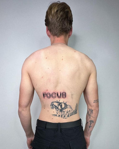 Discreet lower back tattoo for men featuring fine line art and subtle shading, positioned just above the waistline.