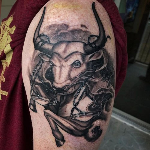 Taurus and Libra zodiac symbols balanced in a tattoo on the upper arm