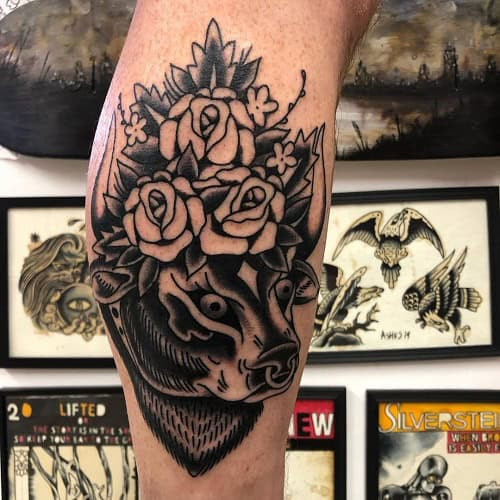 Taurus bull tattoo with roses surrounding the design on the forearm
