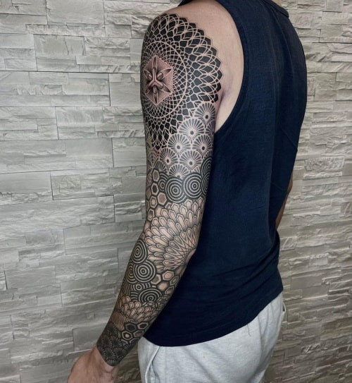 Tessellation geometric sleeve tattoo showcasing a sleeve design with repeating geometric patterns that interlock seamlessly, creating a visually complex and continuous design.