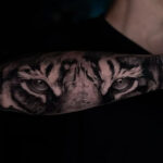 Intense tiger eyes tattoo on forearm