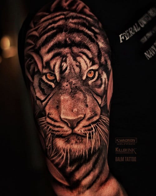 Symmetrical tiger face tattoo on upper arm