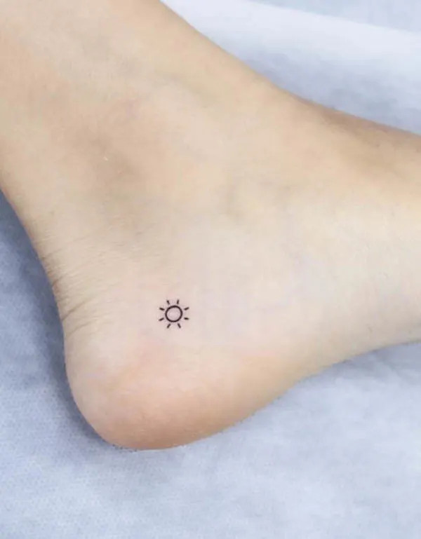 Tiny sun ankle tattoo, a symbol of hope and life, radiating positive energy and optimism