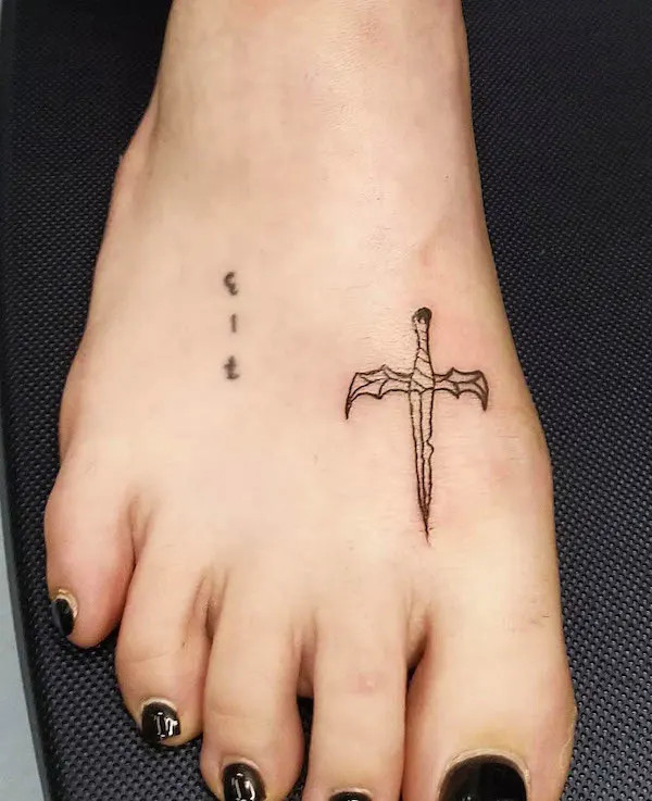 Tiny sword foot tattoo, symbolizing strength, courage, and inner power, a minimalist yet impactful design