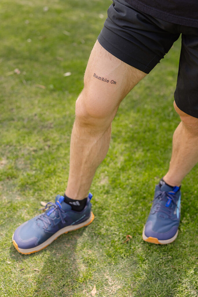 Tattoo of &quot;Ramble On&quot; lyrics and running symbol on Tommy M.'s leg, representing his brain tumor journey, music, and running passion.