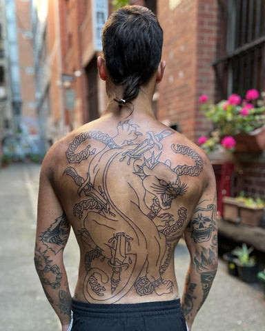 Classic traditional back tattoo for men featuring bold lines, bright colors, and iconic imagery like eagles and roses, symbolizing classic symbolism.