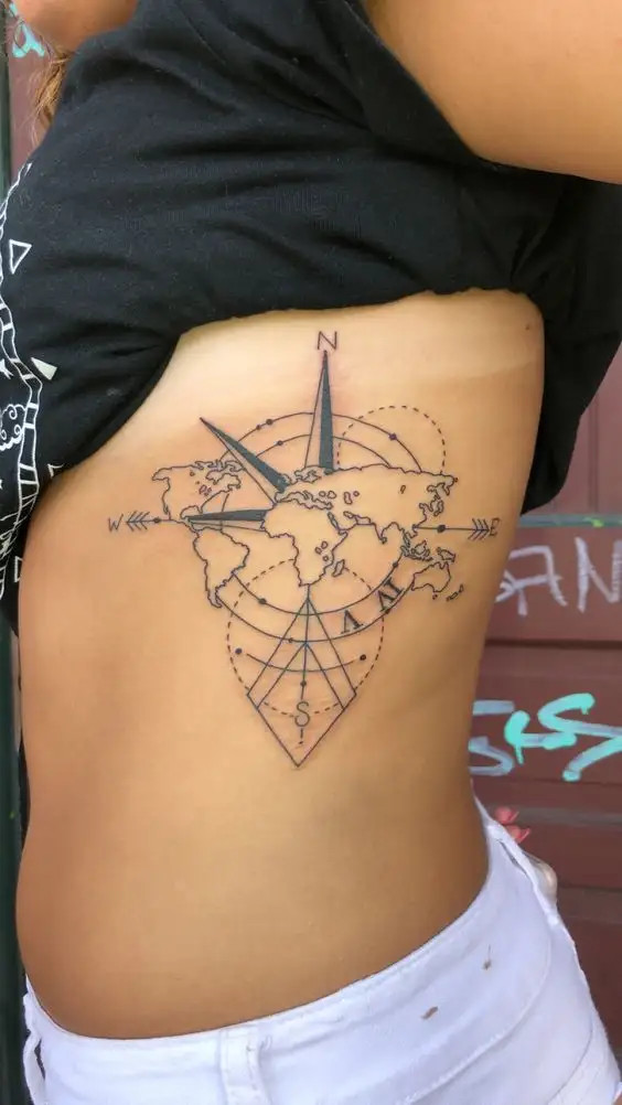 World map and compass travel themed tattoo on the rib cage