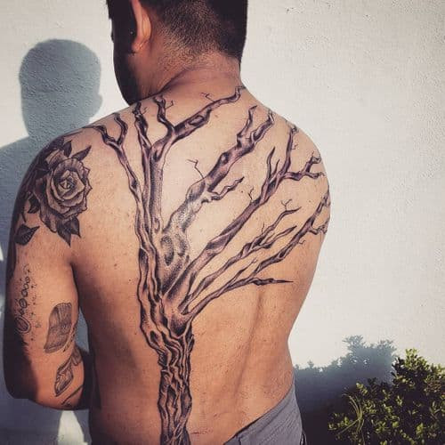 Simple tree silhouette tattoo on the arm, a minimalist men tattoo idea representing nature.