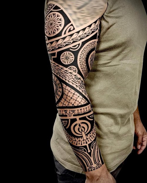 Tribal arm tattoo on a man's arm, showcasing a tribal design on the bicep area.