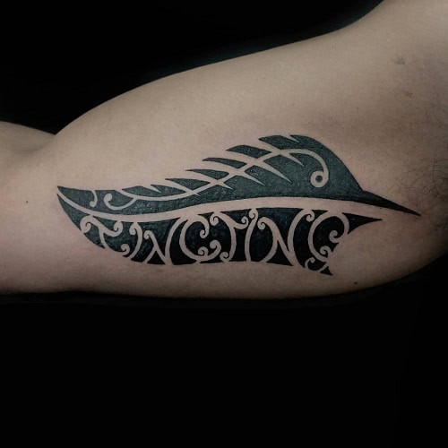 Tribal feather tattoo on a man's arm, depicting a feather with tribal patterns and detailed linework.