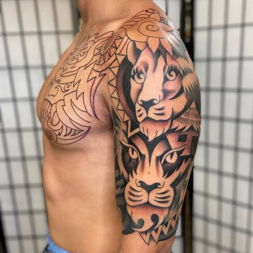 Tribal lion tattoo on a man's shoulder, showcasing a fierce lion head with tribal design elements.