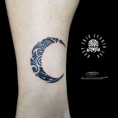 Tribal moon tattoo on a man's forearm, featuring a crescent moon with tribal patterns and shading.