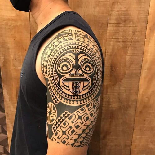 Tribal shoulder tattoo on a man's shoulder, featuring a bold tribal design extending onto the upper arm.