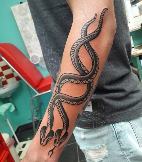 Tribal snake tattoo on a man's leg, depicting a snake winding around the leg with tribal patterns.