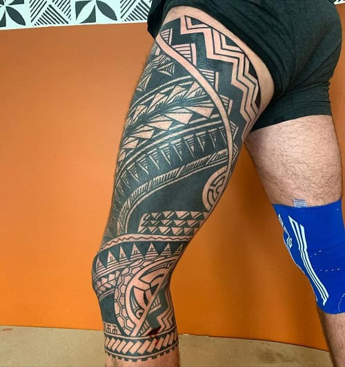 Tribal thigh tattoo on a man's thigh, showcasing a large and detailed tribal design covering the thigh area.