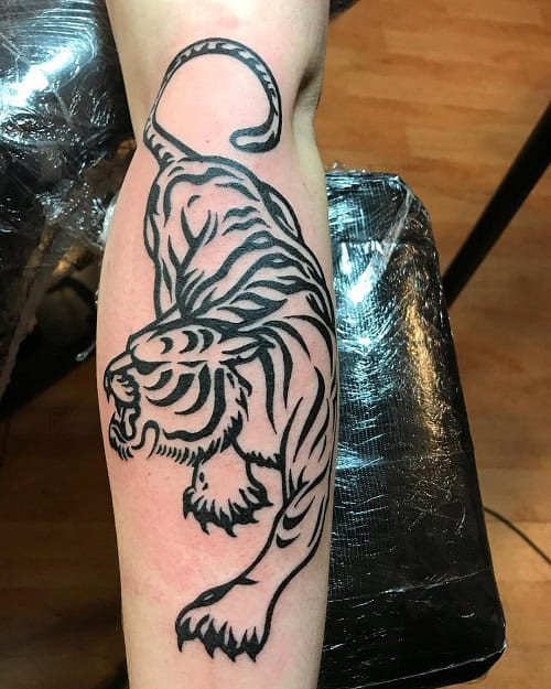 Tribal tiger tattoo on a man's arm, displaying a tiger's face with distinctive tribal stripes.