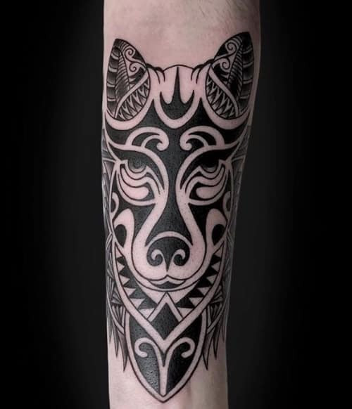 A detailed tribal wolf tattoo on a man's shoulder, featuring bold black linework and traditional patterns to symbolize strength and cultural heritage.