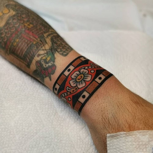 Tribal wrist tattoo on a man's wrist, featuring a smaller tribal design around the wrist.