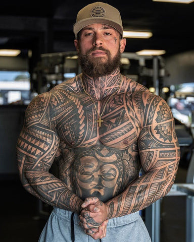 A man showcasing a tribal chest tattoo with bold black lines and intricate geometric patterns, reflecting heritage and strength.