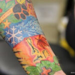 Close-up of leaf tattoos and red shading on Ed Sheeran's lower arm.