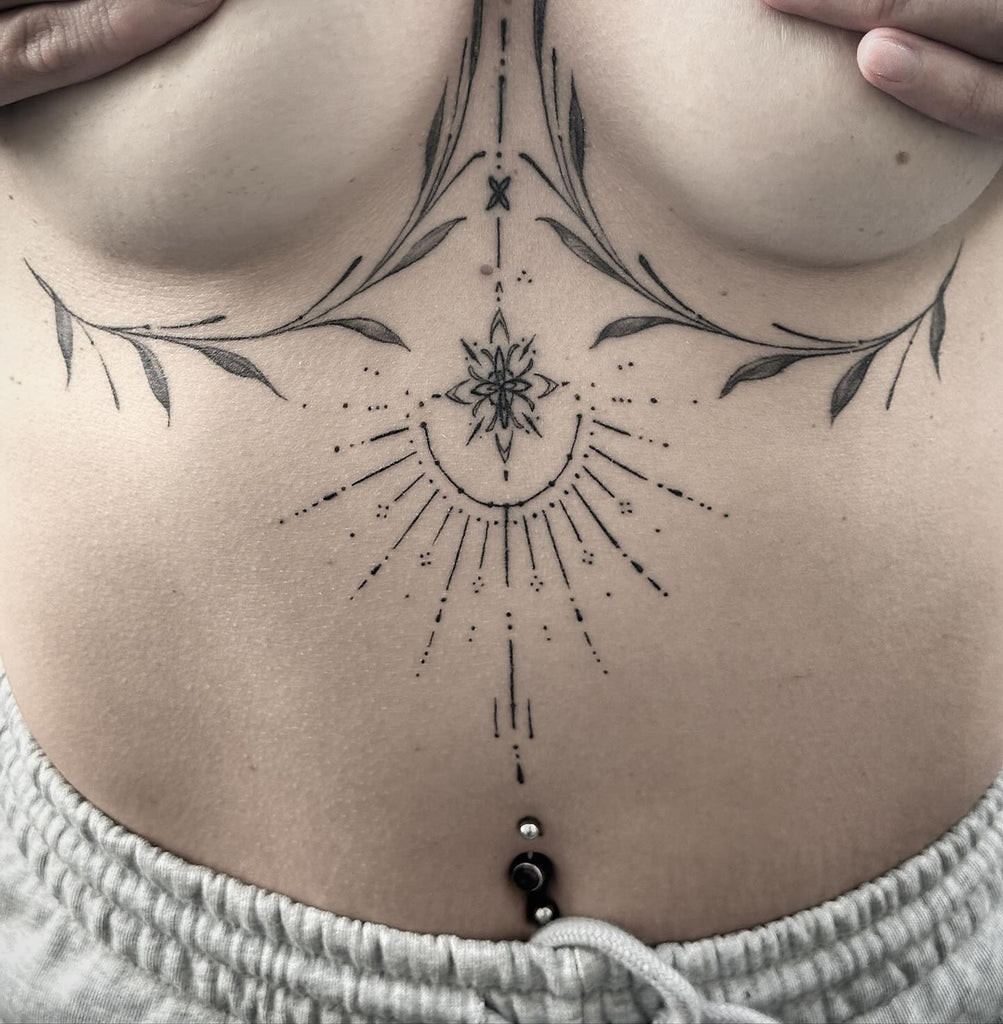 Lace under breast tattoo with subtle pastel color accents