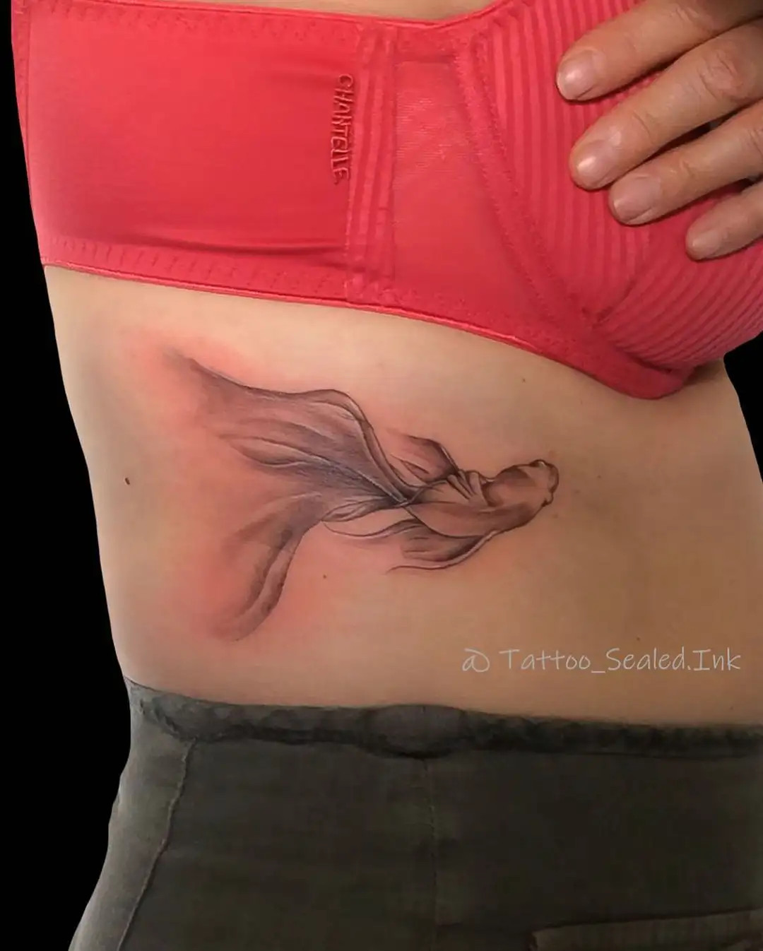 Graceful veil fish tattoo on the rib cage symbolizing intuition