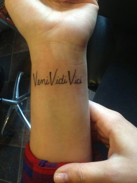 Veni Vidi Vici phrase tattoo on wrist, strong sans-serif font.