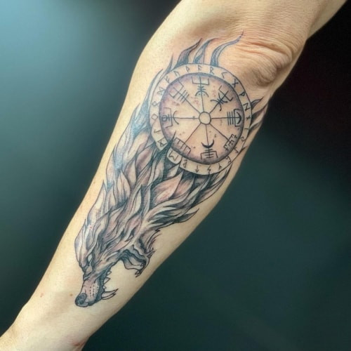 A Viking wolf tattoo on a man's forearm, incorporating Norse knotwork and symbols to represent the complex duality of strength, protection, and mythological connection.