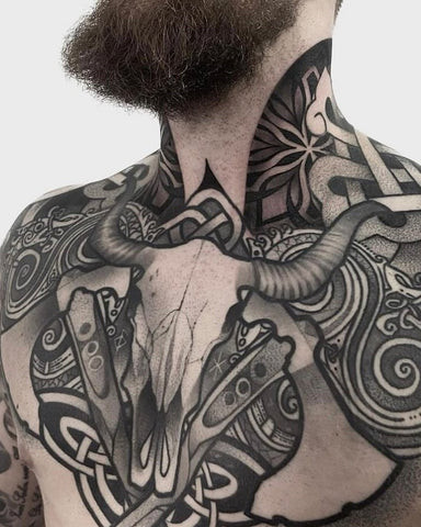 Man with a Viking chest tattoo featuring Norse symbols and runes