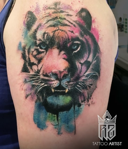 Watercolor wolf tattoo on the arm, a vibrant and artistic men tattoo idea.