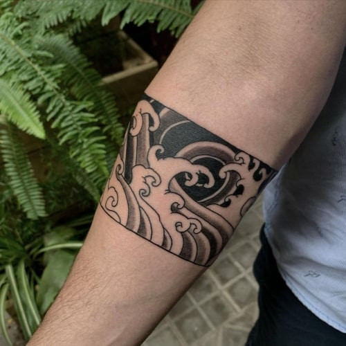 Two wave tattoos on men, one on the forearm with a realistic wave and another on the arm with a minimalist wave outline.