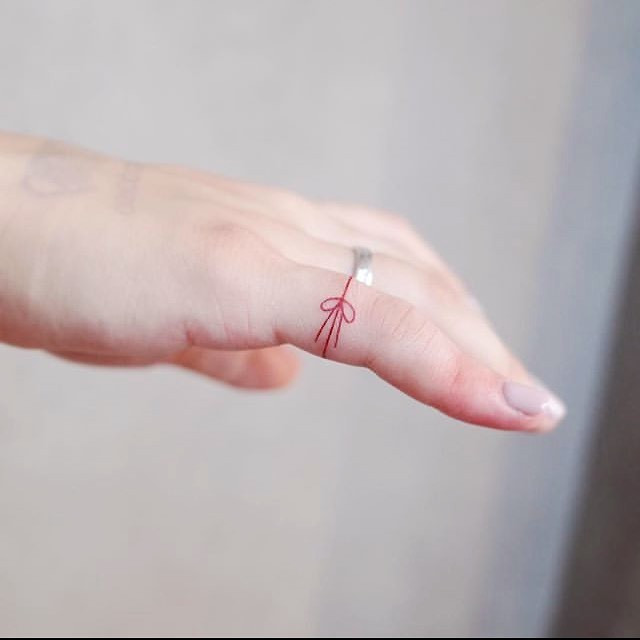 Ribbon ring tattoo on the pinky finger