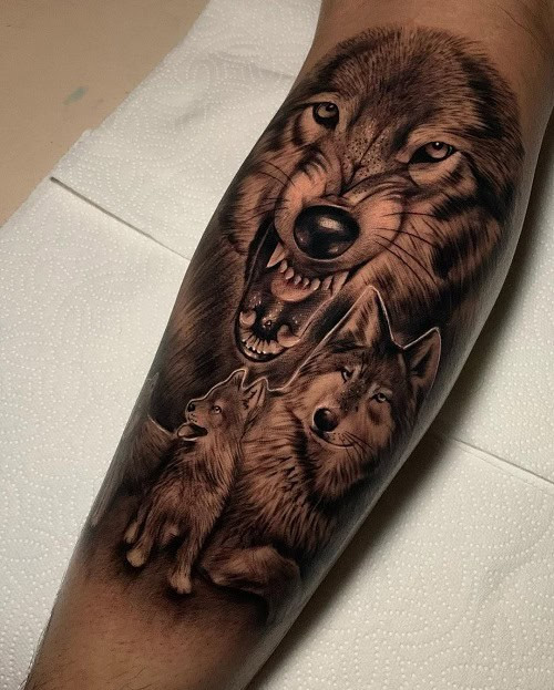 Wolf family howling at the moon tattoo on a man's arm, symbolizing pack loyalty and family bonds.