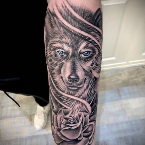 A wolf with rose tattoo on a man's chest, combining a detailed wolf with vibrant red roses, symbolizing duality of character, affection, and a balance between strength and tenderness.