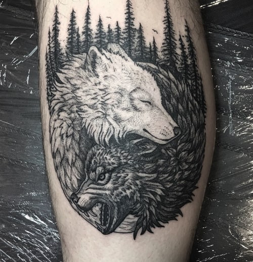 A wolf yin yang tattoo on a man's back, integrating the yin yang symbol with wolf imagery to represent inner balance, harmony of opposites, and the dualistic nature of the wolf.