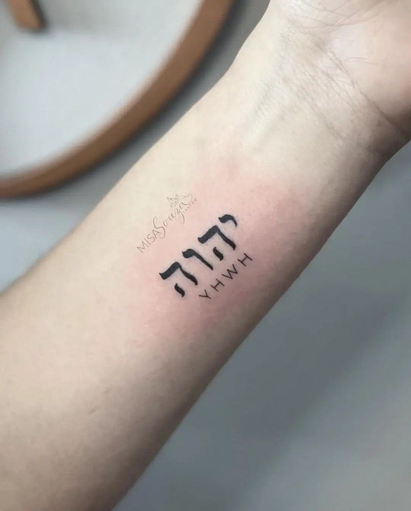 Yahweh Tattoo on the wrist with a simple Hebrew script and a cross symbol