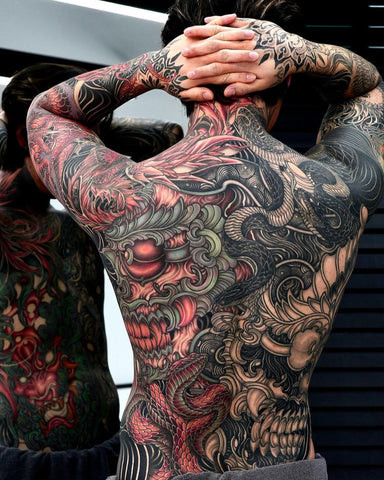 A full Yakuza back tattoo featuring intricate Japanese designs like dragons and koi fish, symbolizing loyalty and courage.