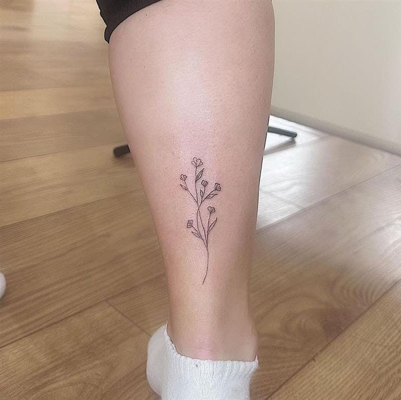 Flower sprig ankle tattoo, delicate floral vine design for ankle.