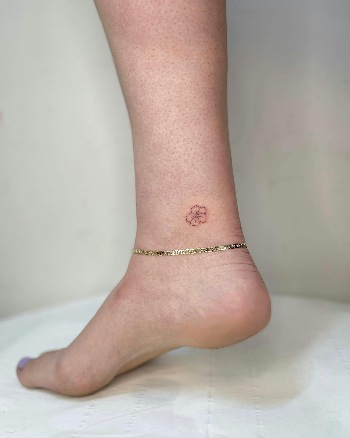 Hibiscus ankle tattoo, single hibiscus flower on woman's ankle.