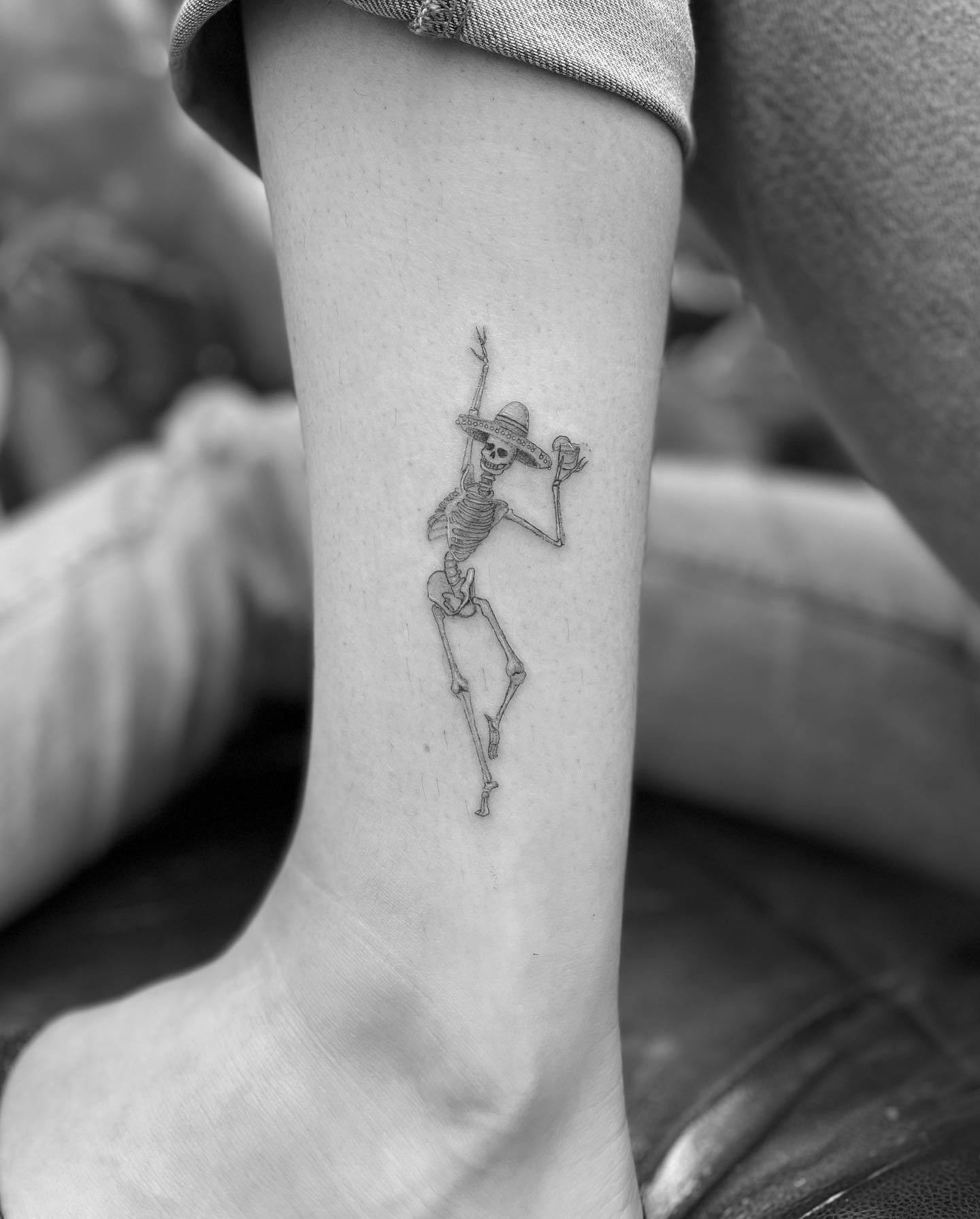 Skeleton ankle tattoo, quirky dancing skeleton design on ankle.