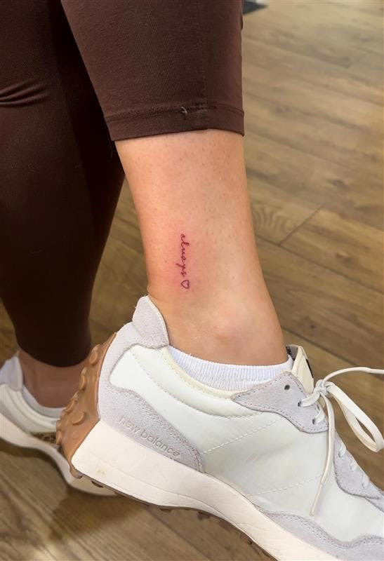 Red script ankle tattoo, quote in red ink on female ankle.