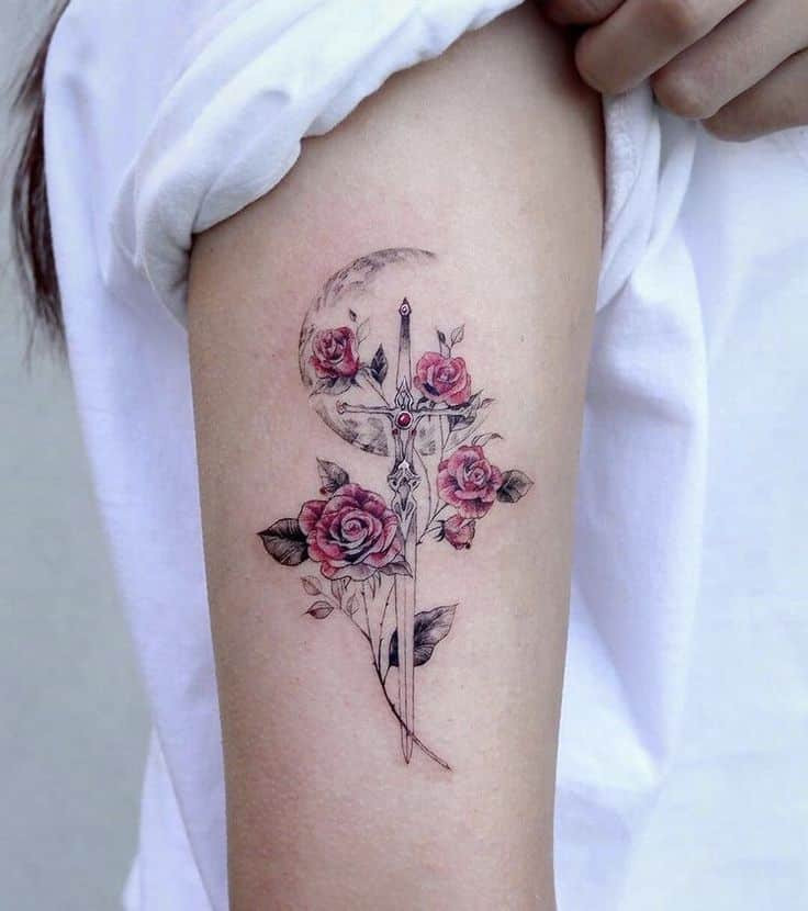 Sword and roses tattoo on upper arm, featuring intricate design elements and delicate shading.
