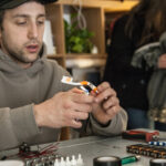 Bending a toothbrush frame to create a DIY tattoo gun base, illustrating the process of heating and shaping the plastic.