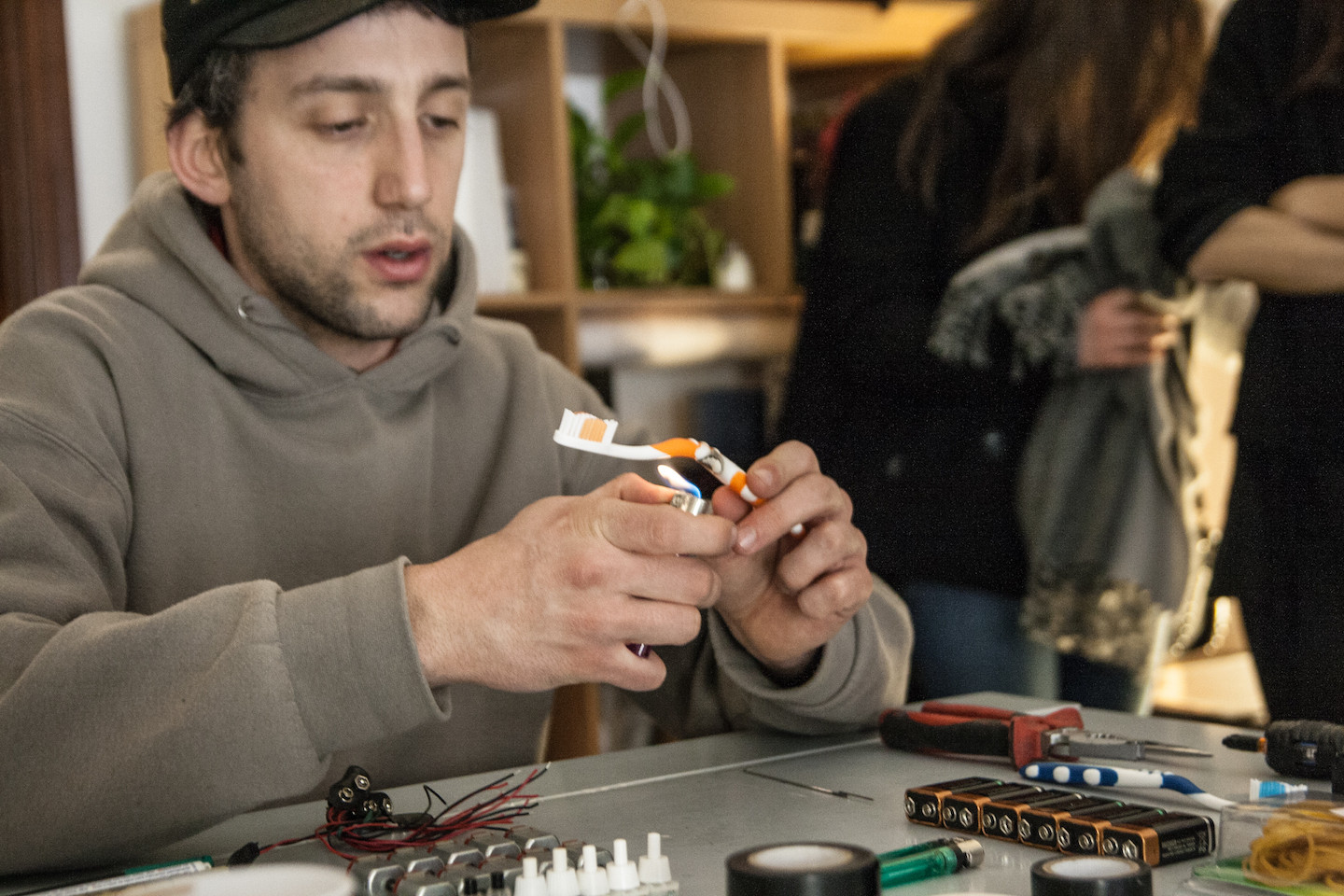 Bending a toothbrush frame to create a DIY tattoo gun base, illustrating the process of heating and shaping the plastic.
