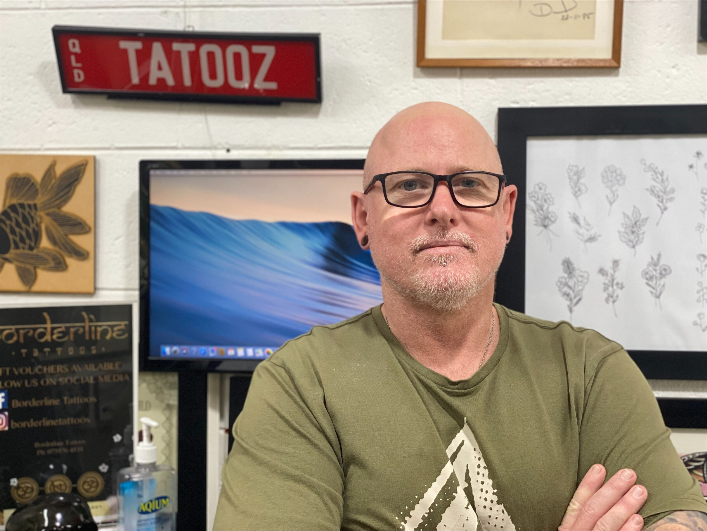 A man stands behind art at a tattoo shop