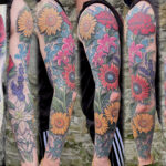 An arm with a tattoo sleeve and two hands working on it