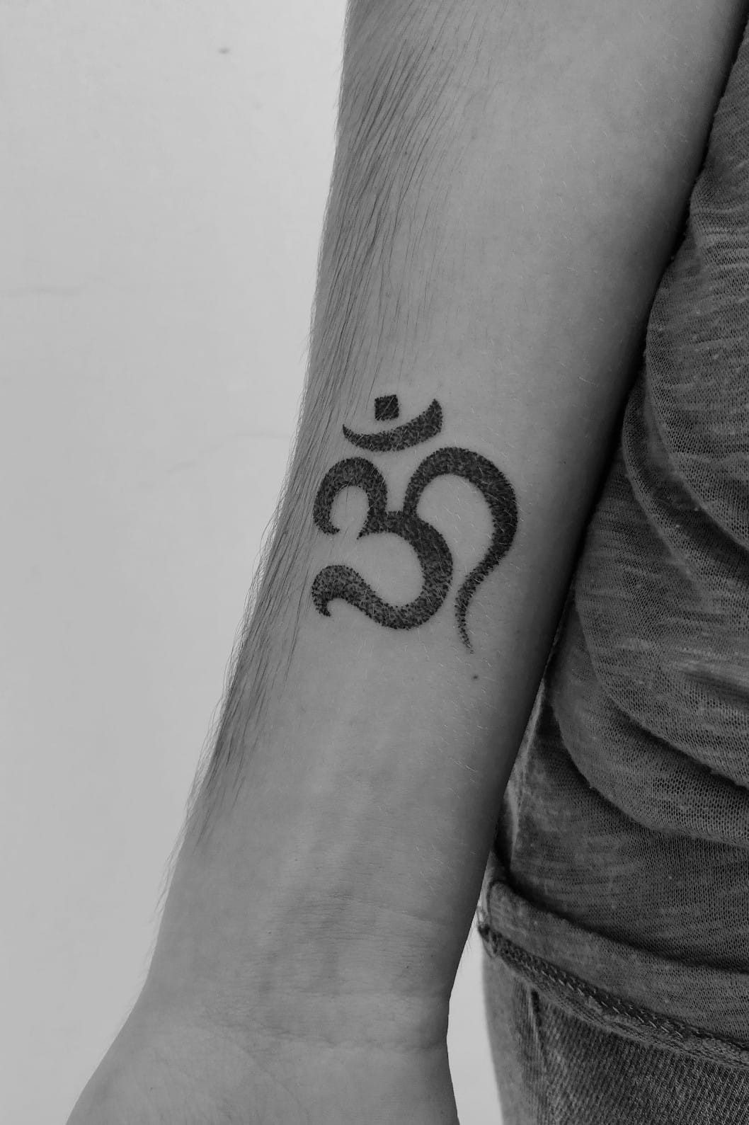 A close-up of a finger tattoo showcasing the Om symbol.